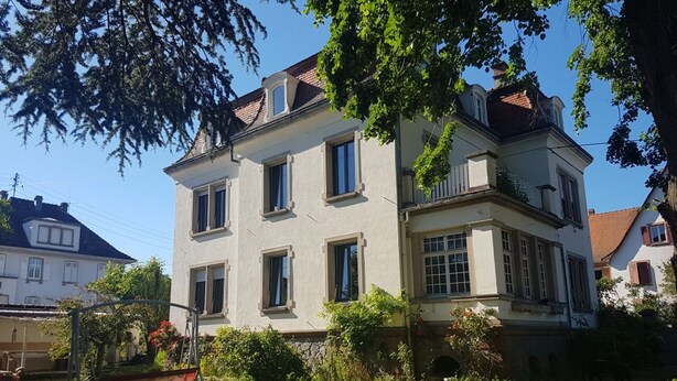 A two-story building with a balcony and a swing set in the yard. - Apartment 100 m² in a mansion (Munster)