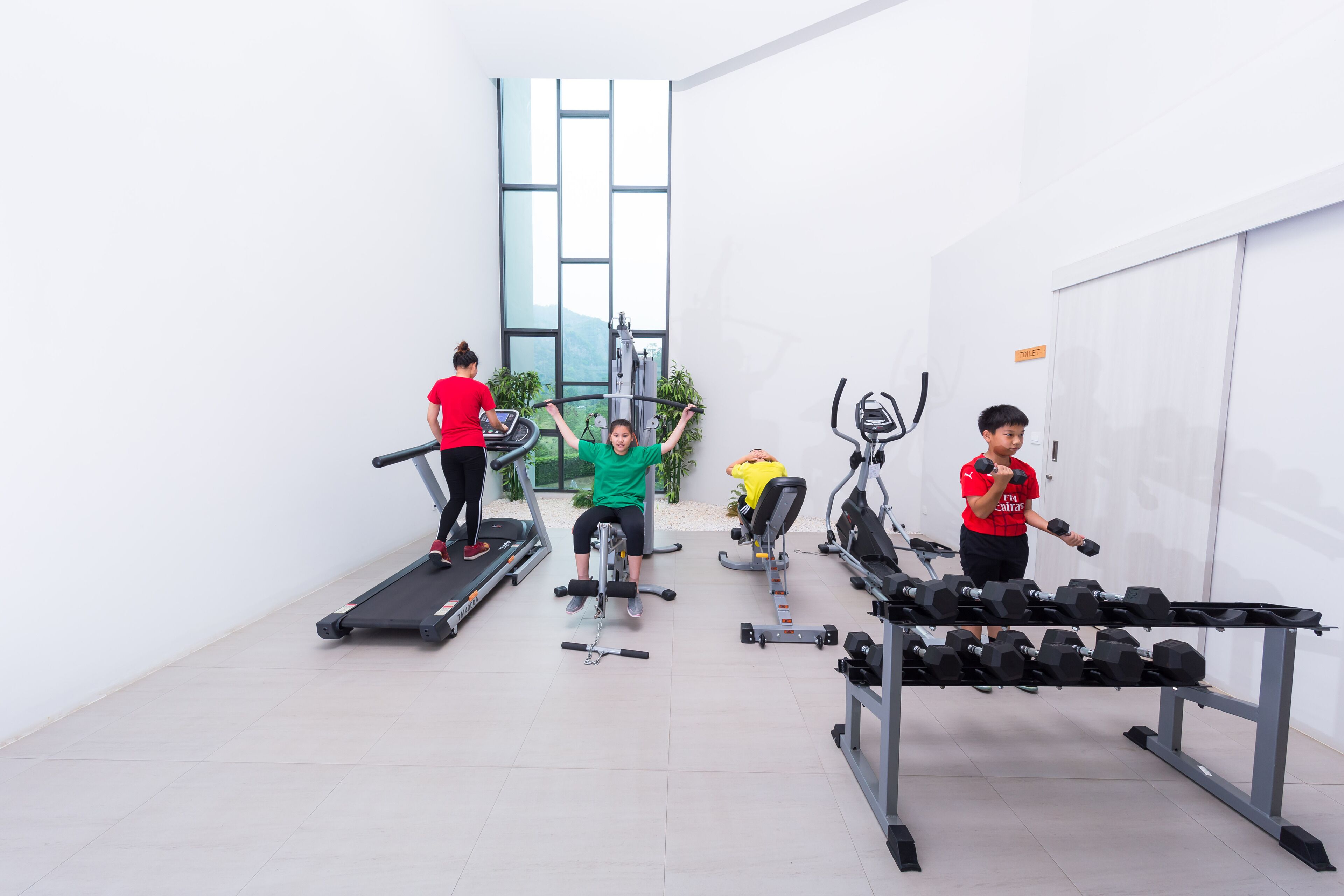 A gym with treadmills, weight machines, and a rack of dumbbells.
