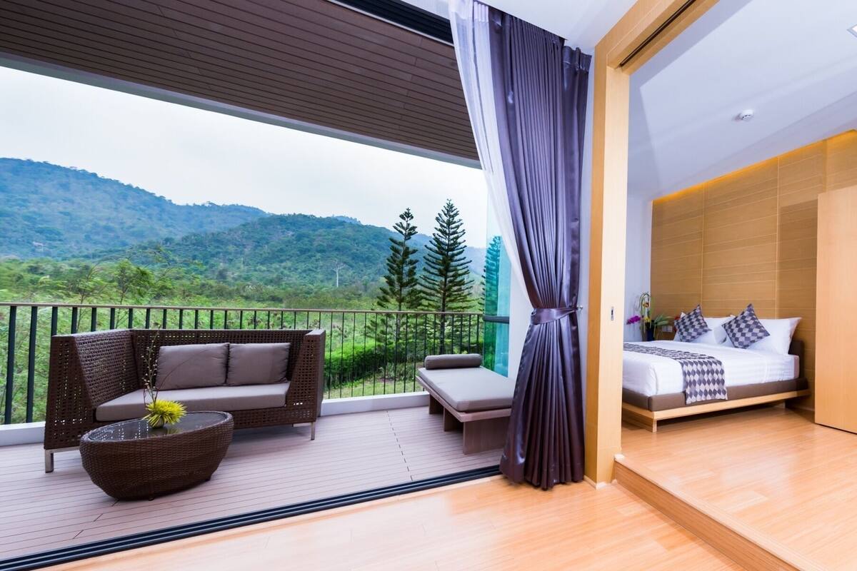 A balcony with a sofa, a small table, and a view of a mountainous landscape.