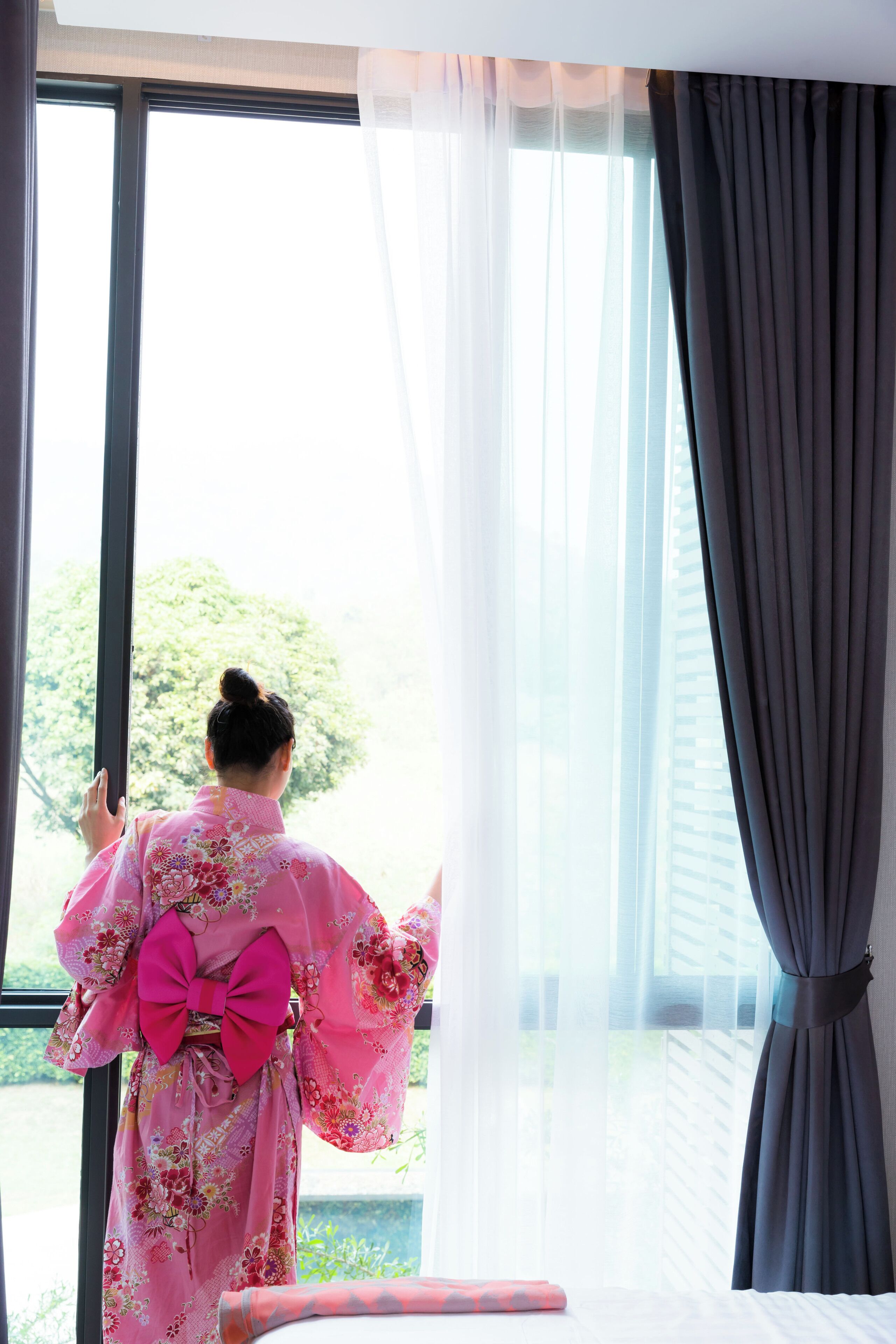 A room with a large window, a bed, and a person in traditional attire.