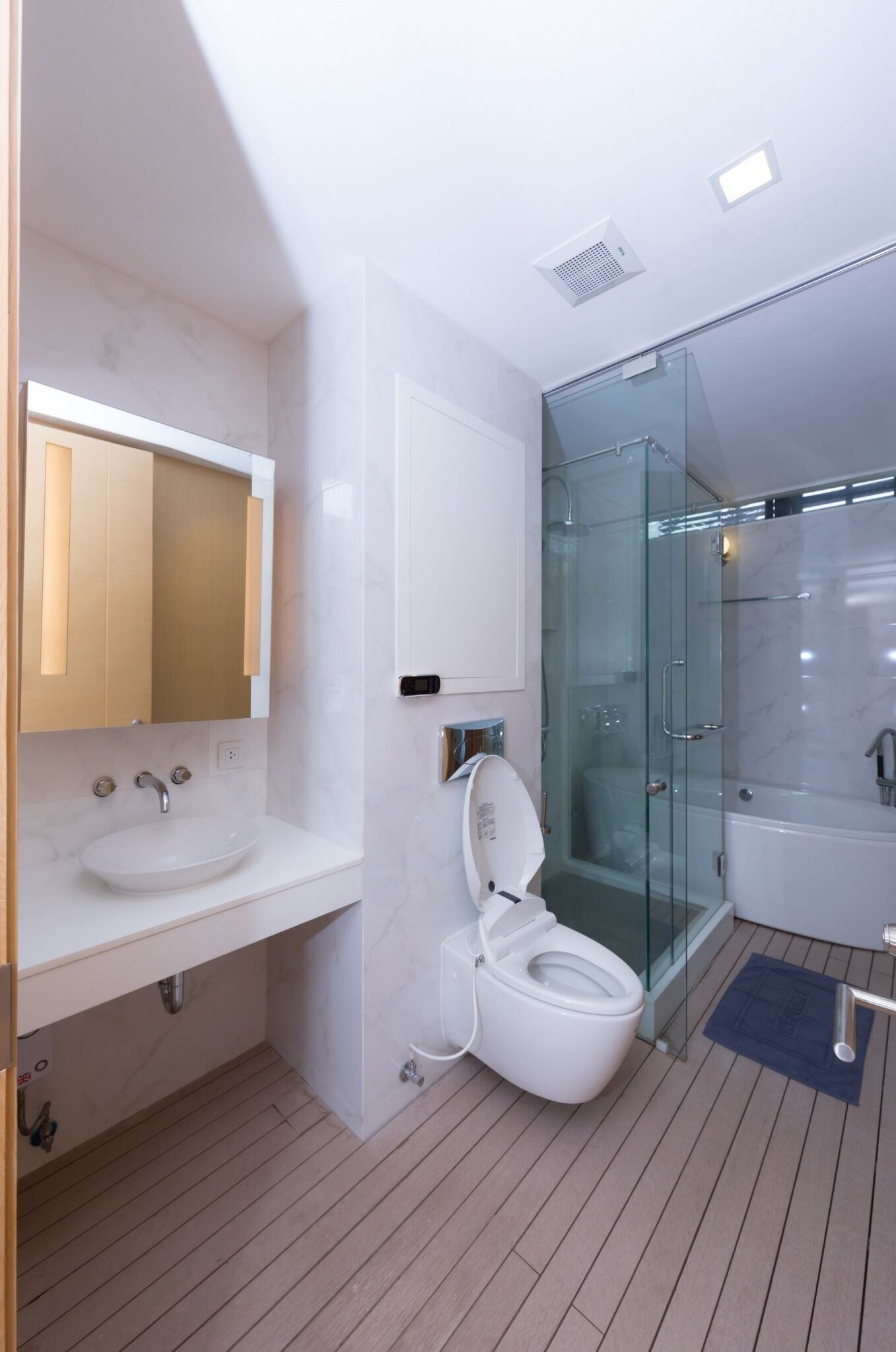 A modern bathroom with a glass-enclosed shower, a white sink, and a toilet.