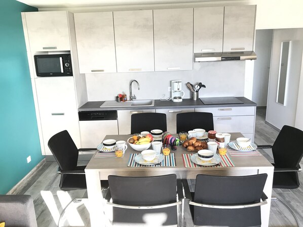 A modern kitchen with white cabinets, a built-in microwave, and a stainless steel range hood.