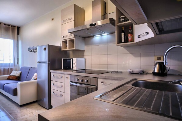 Uma cozinha moderna com forno embutido, micro-ondas e uma pia de aço inoxidável.