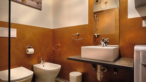A bathroom with a bidet, toilet, and sink.