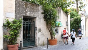 A narrow cobblestone street with a building featuring a green gate and a sign reading "Piazza Spirito Santo." - Palazzo Gargano (Amalfi)