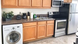 A kitchen with wooden cabinets, a microwave, a stove, a refrigerator, a sink, and a washing machine. - 303/C Little Italy double balcony Loft /Parking (San Diego)