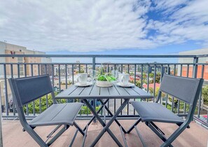 A balcony with a table and two chairs, a potted plant, and two white cups. - 303/C Little Italy double balcony Loft /Parking (San Diego)