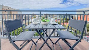 A balcony with a table and two chairs, a potted plant, and two white cups. - 303/C Little Italy double balcony Loft /Parking (San Diego)