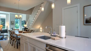 A modern kitchen with a large island, stainless steel appliances, and pendant lighting.