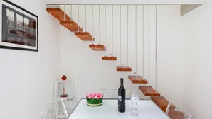 A modern interior with a staircase, a dining table with a bottle and glass, and a framed picture on the wall. - GuestHost - Cute flat in the heart of Monopoli (Monopoli)