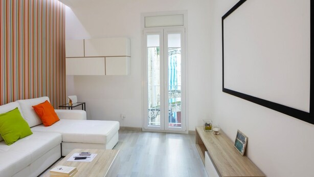 A modern living room with a white sofa, a coffee table, and a view through a glass door to the outside. - GuestHost - Cute flat in the heart of Monopoli (Monopoli)