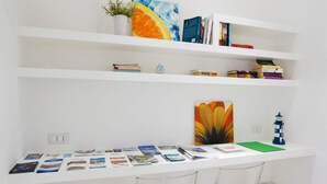 A white desk with books, a plant, and a painting. - GuestHost - Cute flat in the heart of Monopoli (Monopoli)