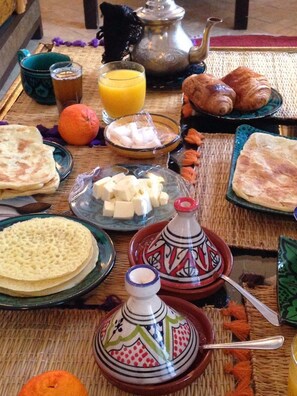 A breakfast setting with various food items and a teapot on a woven mat. - RIAD CLEFS D'ORIENT (Marrakech)