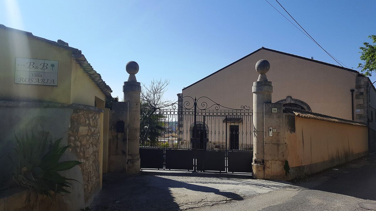 Une entrée fermée par un portail mène à un immeuble sur lequel on peut lire l’inscription : « B&B Villa ROSARIA ».