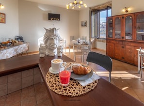 A dining area with a table set for two, featuring a croissant, a cup of coffee, and a glass of red drink. - Villa Rosaria (Noto)