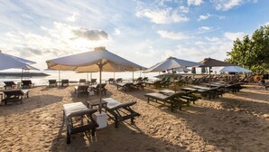 A beach with sun loungers and umbrellas, a sandy beach, and a view of the ocean. - Villa Pantai Karang (Denpasar)