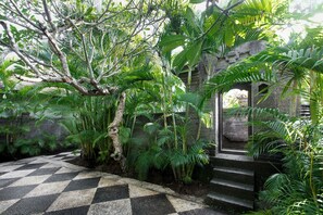 A tropical garden with a checkered pathway leading to a stone staircase. - Villa Pantai Karang (Denpasar)