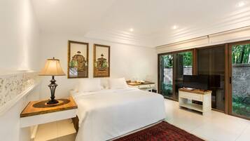 A modern bedroom with a large bed, a bedside table with a lamp, a TV, and a sliding glass door leading to a balcony.