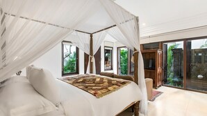 A bedroom with a canopy bed, large windows, and a view of greenery. - Villa Pantai Karang (Denpasar)