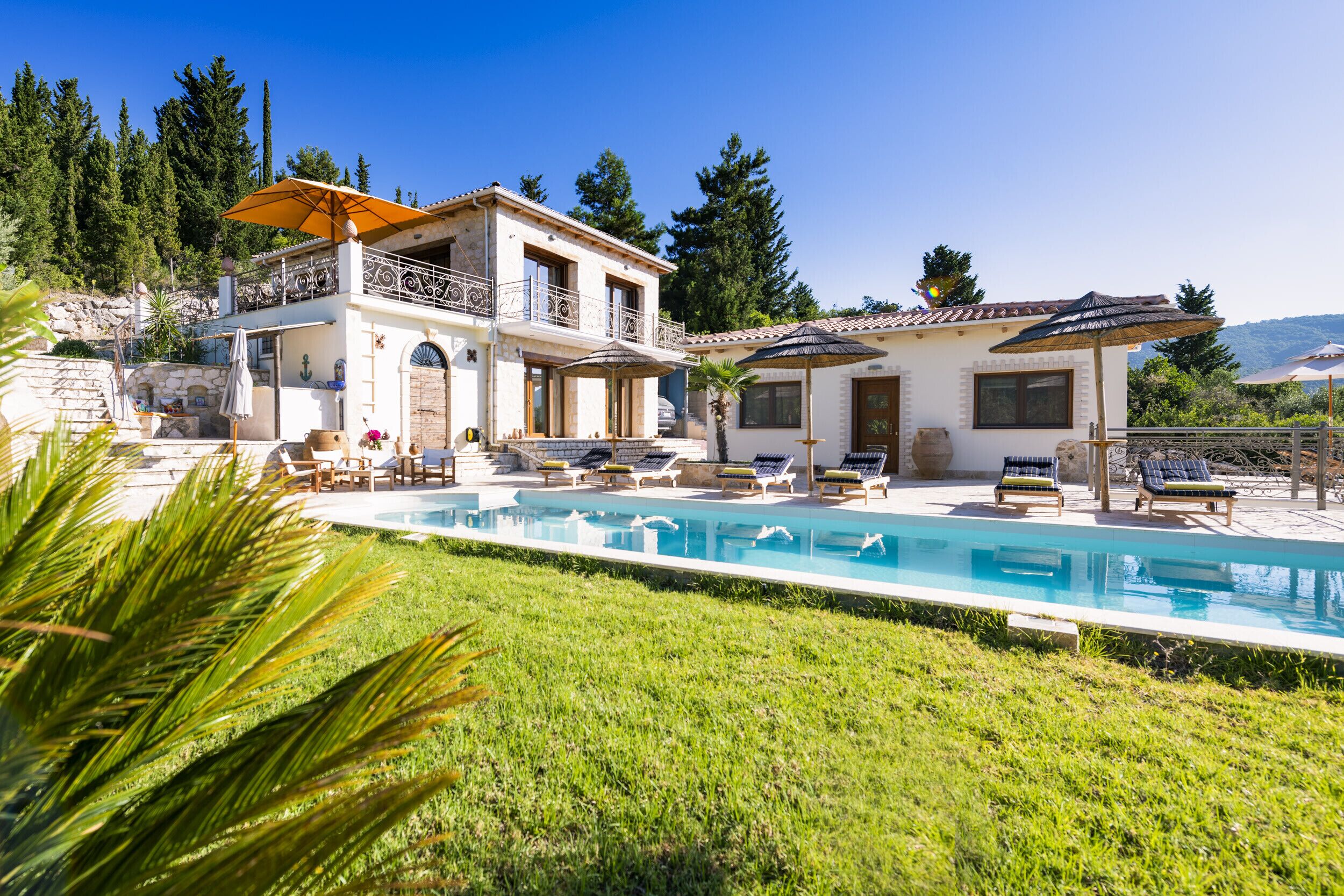 Ein zweistöckiges Haus mit Swimmingpool, Sitzgelegenheiten im Freien und Blick auf die umliegende Landschaft.