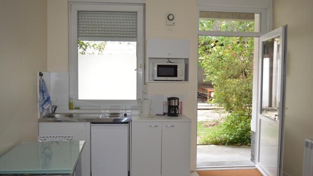 A compact kitchen with a microwave, sink, and a small dining area.