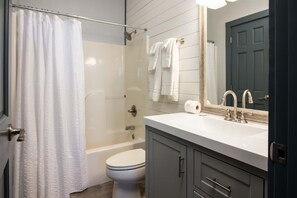 A bathroom with a shower, toilet, and sink.