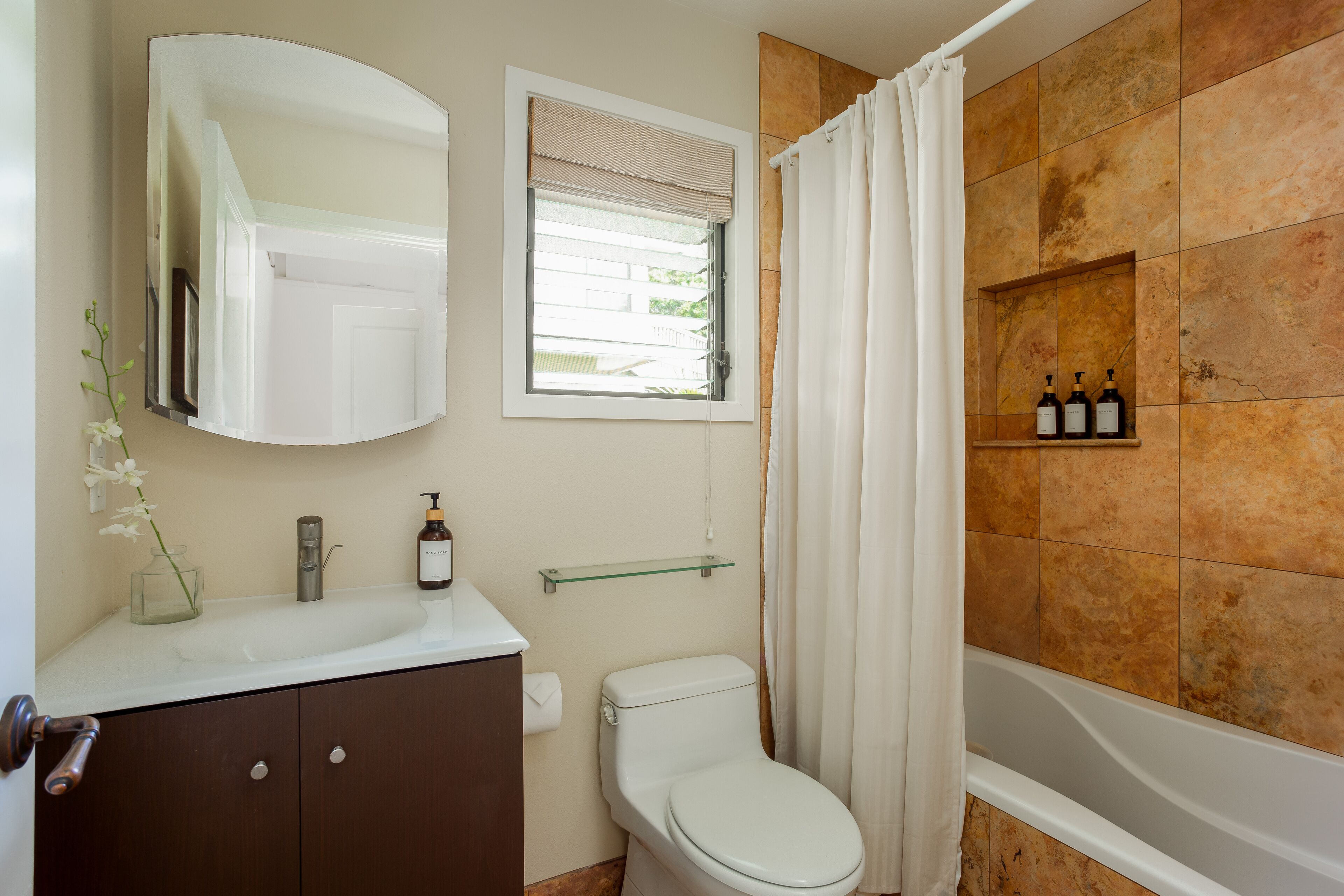 A bathroom with a white sink, a toilet, a bathtub, and a mirror above the sink.