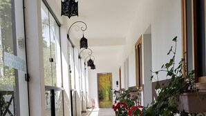 Um corredor coberto com piso estampado, plantas em vasos e lanternas penduradas.