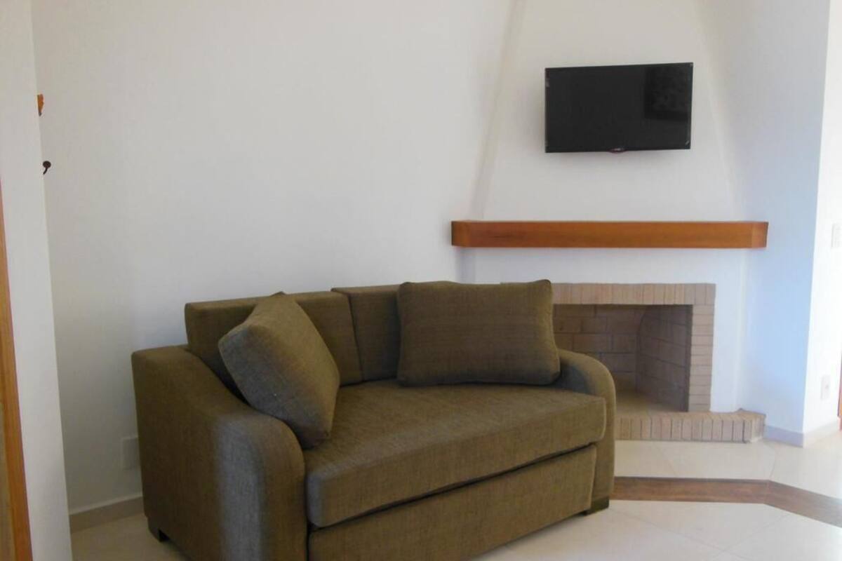 Ein Wohnzimmer mit einer Couch, einem flachbildfernseher an der Wand und einem Kamin.