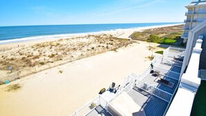 Blick auf einen Strand vom Hotelbalkon mit Sandstrand, Meer und einer Umzäunung.