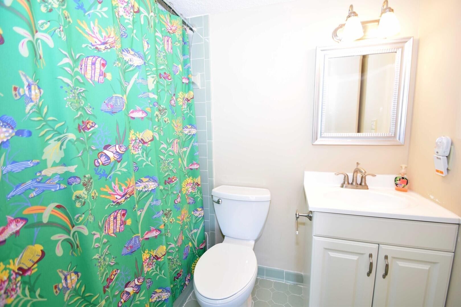 A bathroom with a toilet, sink, and mirror.