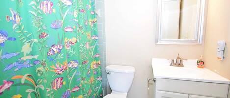 Et badeværelse med toilet, vask og spejl.