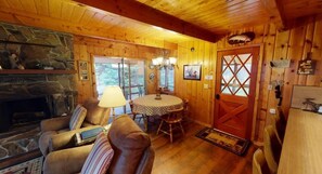 A cozy cabin interior with a stone fireplace, leather sofas, a dining table, and a wooden door with a cross design. - 34 MI to YNP | Waterfront Access | Cozy Retreat (Island Park)