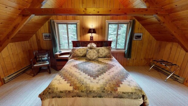 Une chambre confortable située sous les toits, avec un grand lit, deux fenêtres, un bureau et une chaise.