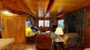 Un intérieur en bois avec une cheminée, un canapé, une table et un téléviseur.