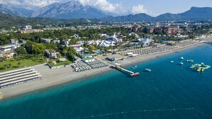 An aerial view of a coastal town with a beach, boats, and a pier. - Simena Comfort Hotel (Kemer)