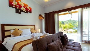 Ein Hotelzimmer mit Bett, Sofa, Blick ins Freie und einem Gemälde an der Wand.