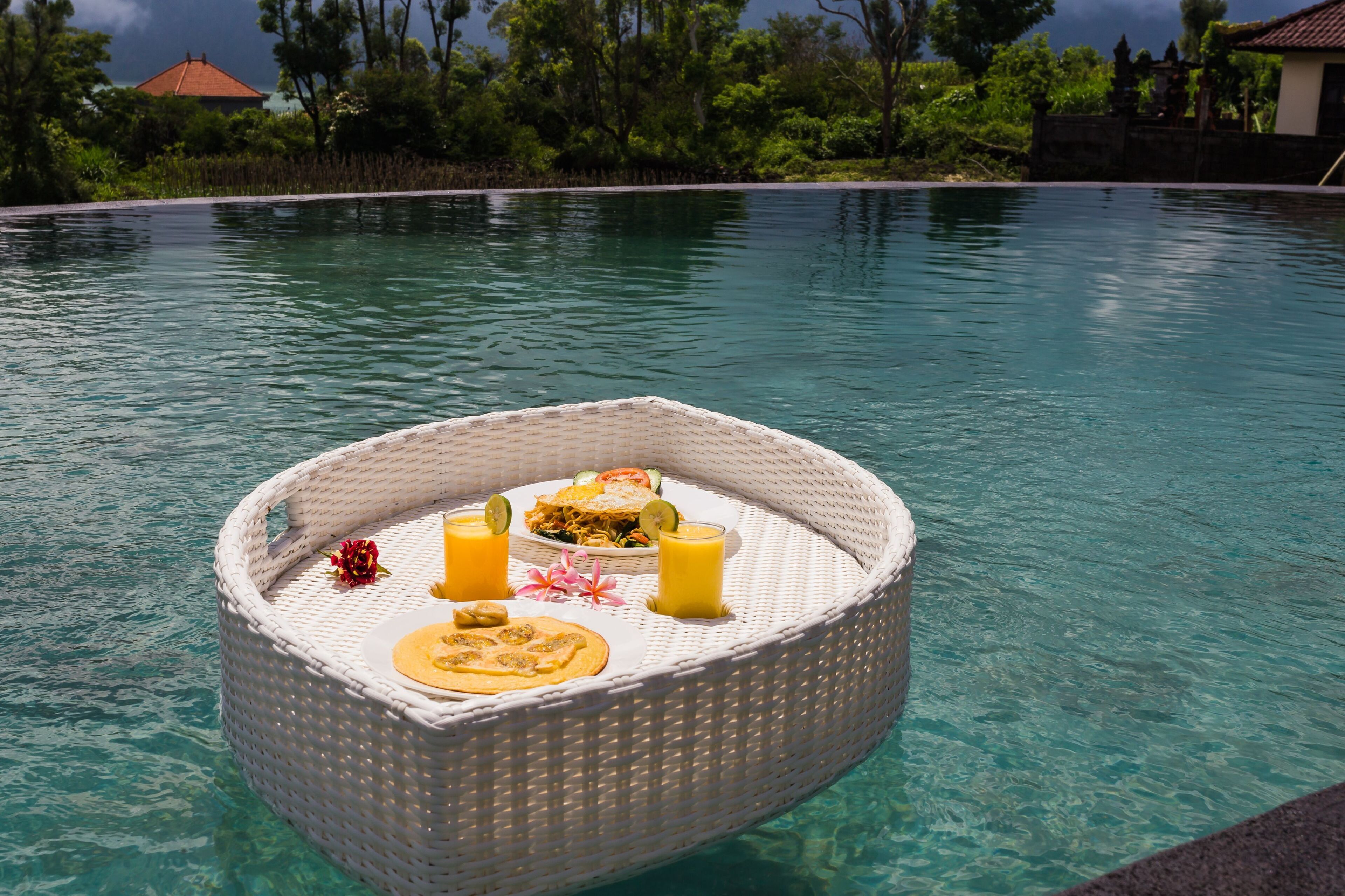 Montaje de comedor flotante con comida y bebidas en una piscina transparente.