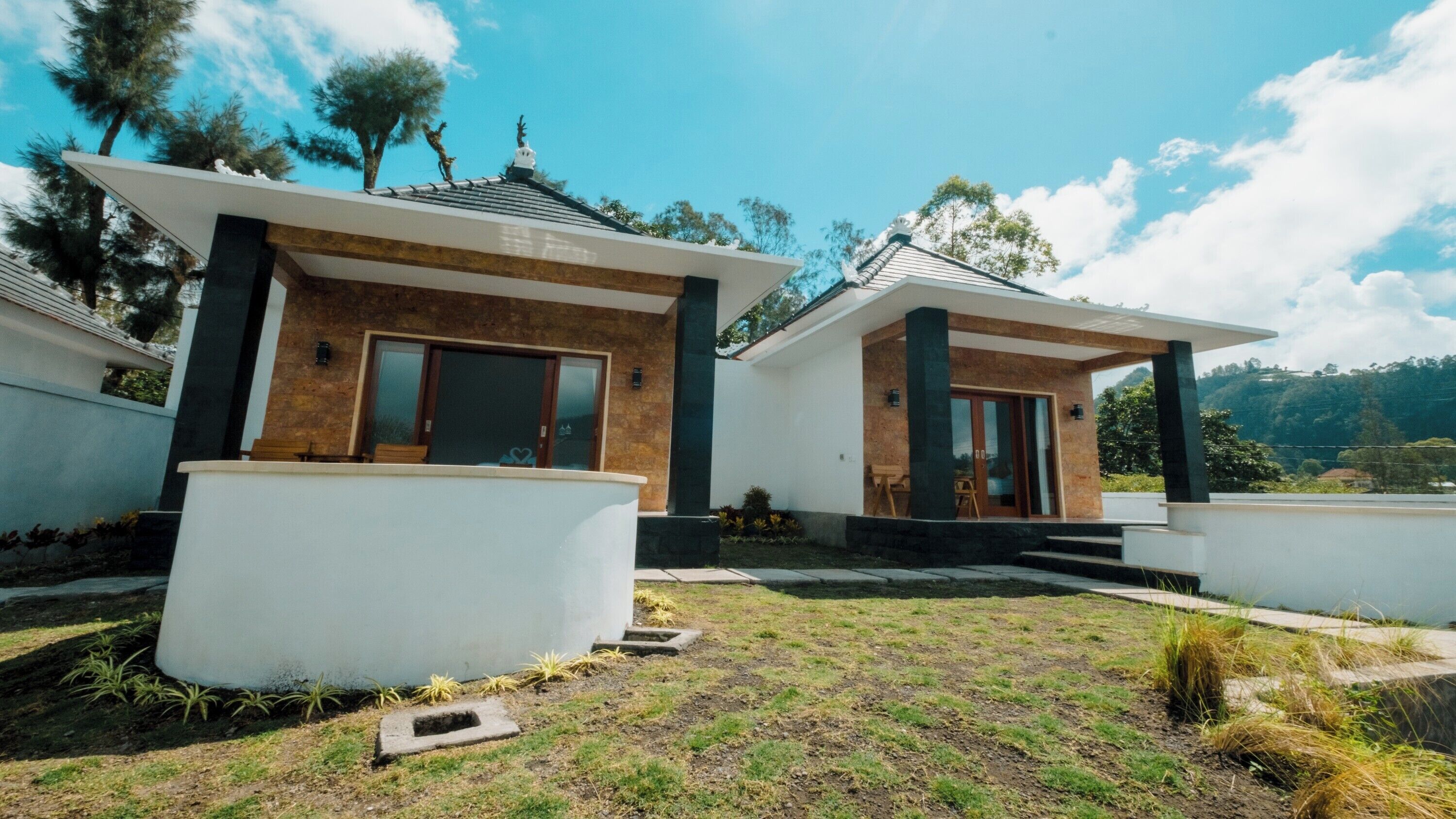 Una casa moderna con due sezioni separate, ciascuna dotata di un balcone e vista sul paesaggio circostante.