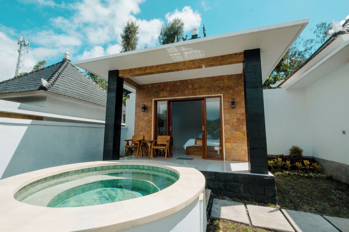 A modern house with a swimming pool, a patio with outdoor furniture, and a large sliding glass door leading to a bedroom.