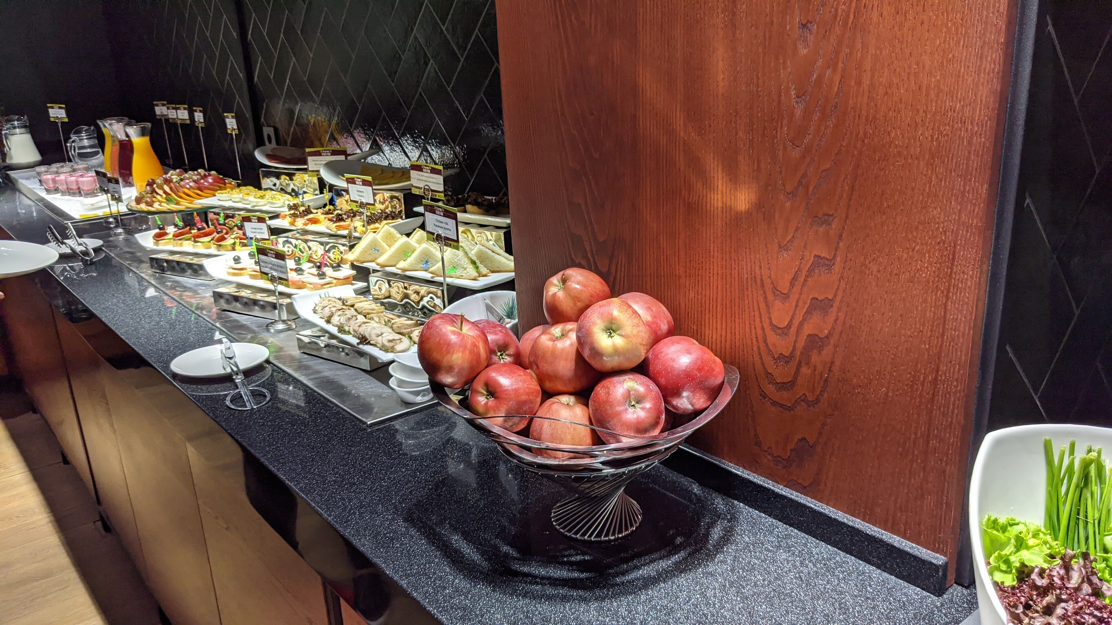 Un buffet proposant une variété d’aliments, notamment des fruits et des sandwichs, disposés sur un comptoir noir.