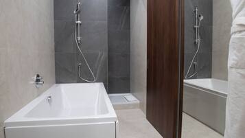 Un baño moderno con una bañera grande, zona de ducha y un espejo.