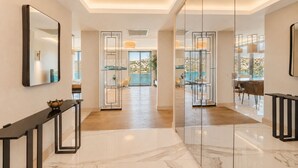 Un hall d’hôtel moderne avec un sol en marbre, une cloison en verre et une vue sur la piscine.