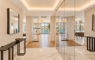 Un moderno hall de hotel con suelo de mármol, una pared de vidrio y vistas a la piscina.
