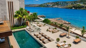 Un espace piscine aménagé sur le toit, avec des chaises longues et une vue sur la mer.
