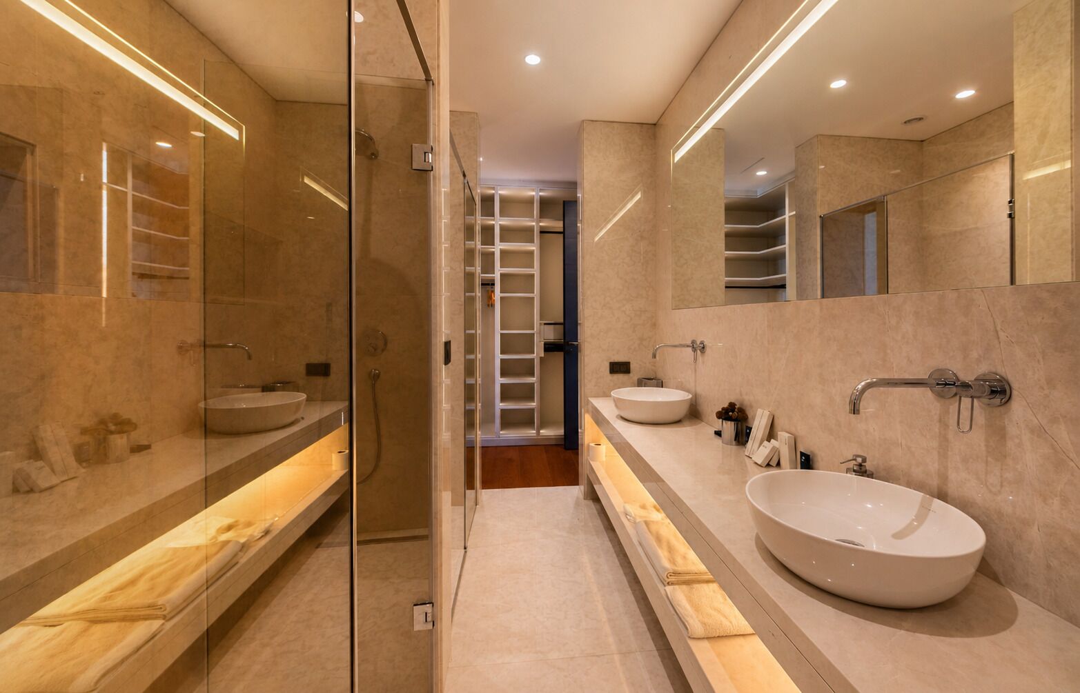 A modern bathroom with a glass shower enclosure, two large sinks, and a mirrored vanity.