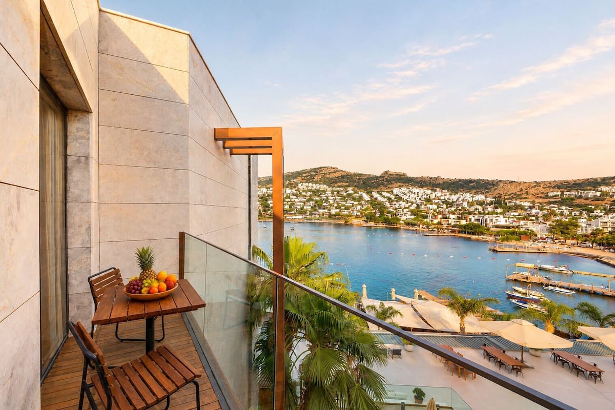 A balcony with a table, chairs, and a bowl of fruit.