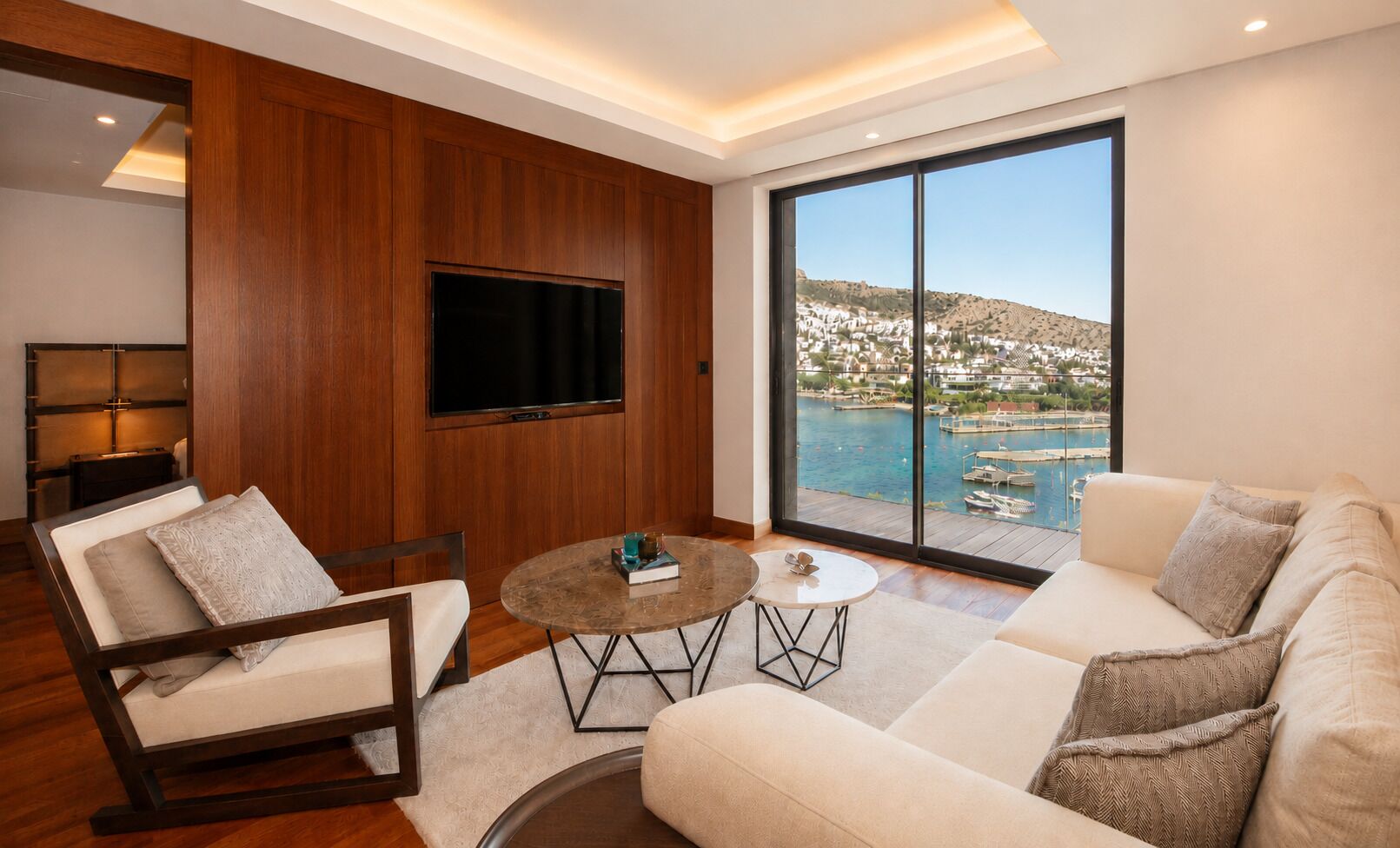 A modern living room with a large TV, a sofa, a chair, and a coffee table.