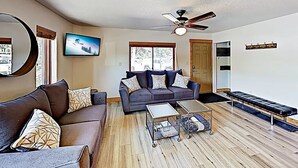 A living room with a dark brown sofa, a grey couch, a coffee table, and a ceiling fan.
