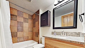 A bathroom with a shower, toilet, and vanity.